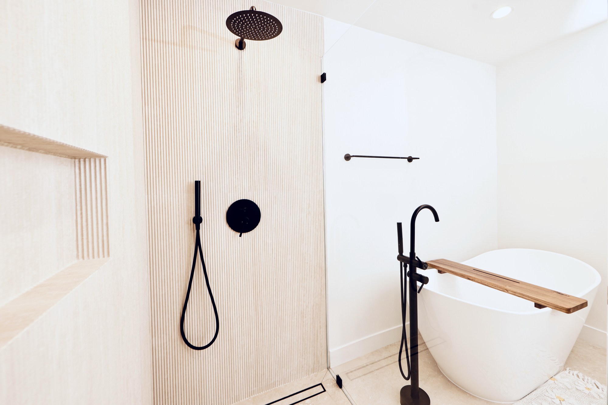 Primary spa bath with freestanding tub, full-height marble, and matte black fixtures